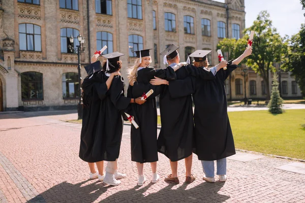 大学の前で隣同士に立つ卒業生. — ストック写真