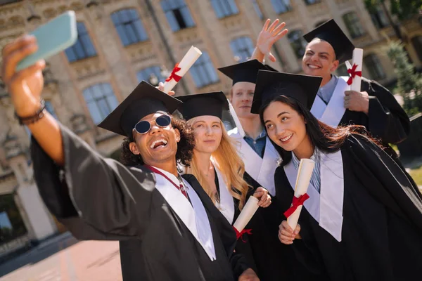 Счастливые выпускники делают селфи рядом с университетом . — стоковое фото
