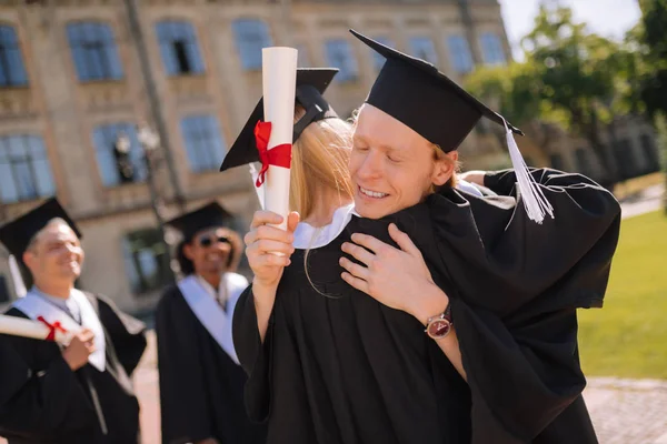 Dois graduados abraçando na frente de sua universidade . — Fotografia de Stock