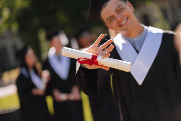 Diploma recém-recebido nas mãos de um graduado orgulhoso . — Fotografia de Stock