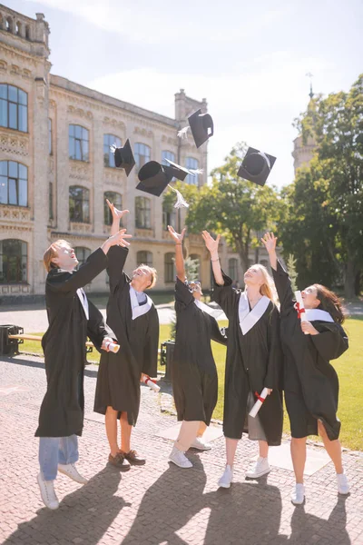 Graduating students throwing their masters caps up.