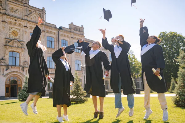 Étudiants diplômés sautant haut avec leurs casquettes . — Photo