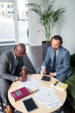 Gri saçlı vergi uzmanının müşterisine danışmanlık yaptığı üst görünüm
