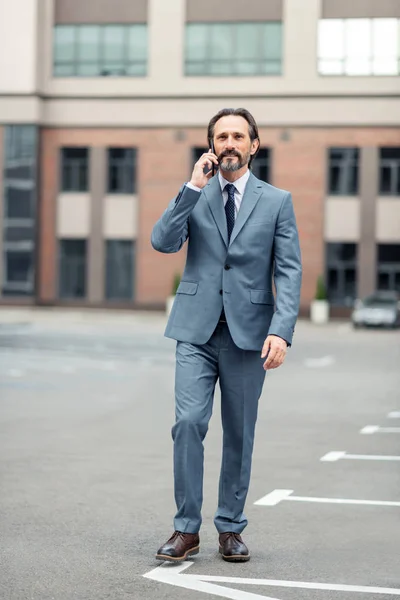 Uomo vestito grigio che chiama collega mentre cammina a piedi — Foto Stock