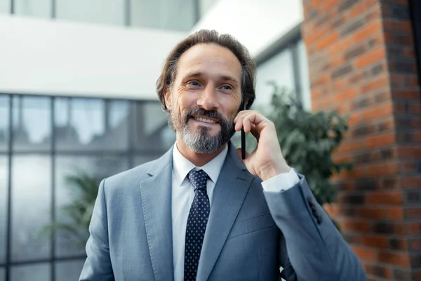 Homme d'affaires portant une cravate élégante souriant tout en recevant un appel téléphonique — Photo