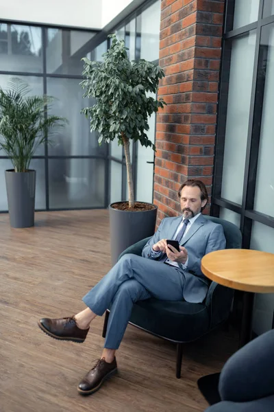 Empresario barbudo usando su teléfono mientras espera a su colega —  Fotos de Stock