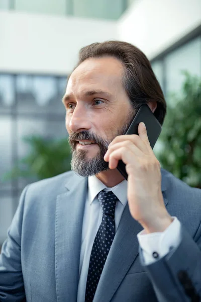 Bearded man draagt grijze jas die zijn zakenpartner belt — Stockfoto