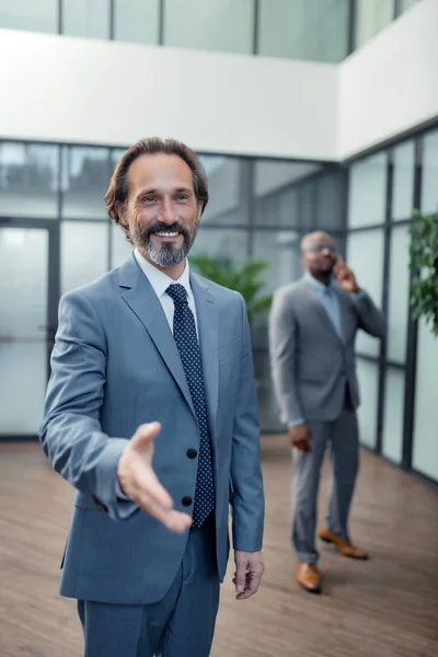 Businessman reaching his hand out to colleague while greeting