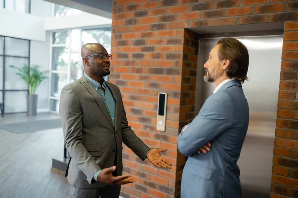 Dos hombres de negocios hablando mientras esperan el ascensor — Foto de Stock