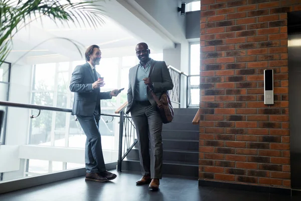 Two businessmen smiling while meeting near the elevator