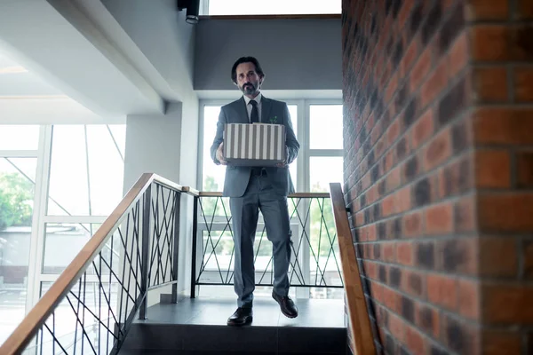 Grey-haired office worker leaving office center after been dismissed