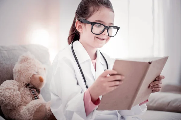 Menina inteligente positivo segurando um livro em suas mãos — Fotografia de Stock