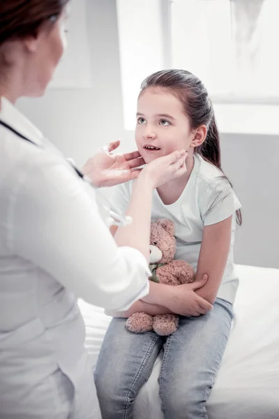 Angenehmes nettes Mädchen sitzt auf dem medizinischen Bett — Stockfoto