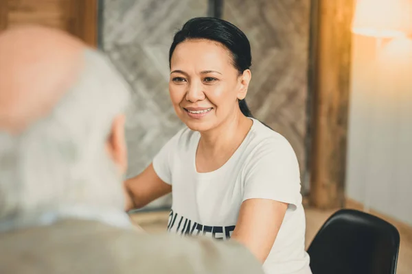 Uśmiechnięta brunetka kobieta delikatnie patrząc na Starzec — Zdjęcie stockowe