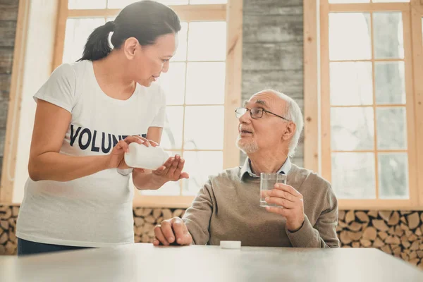 Mujer adulta reflexiva ayudando a hombre de pelo gris con medicamentos — Foto de Stock