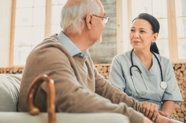 Boynunda stetoskop olan pozitif doktor adamla konuşuyor