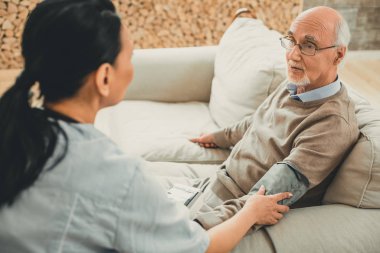 Kan basıncı ölçülen gri saçlı yorgun adam