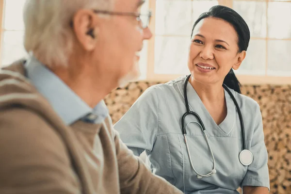 Sorridente gentile medico femminile guardando sul suo vecchio paziente — Foto Stock