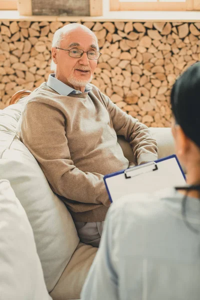 Leende Senior i brun tröja under läkarbesök — Stockfoto