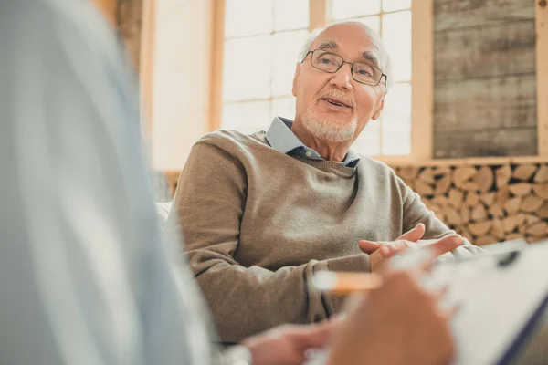 Kale senior in gezellige trui praten met zijn arts — Stockfoto