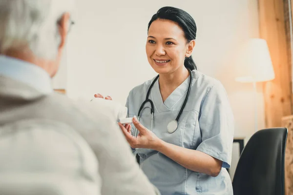 Allegro medico dai capelli scuri che presenta nuovi farmaci al suo paziente — Foto Stock