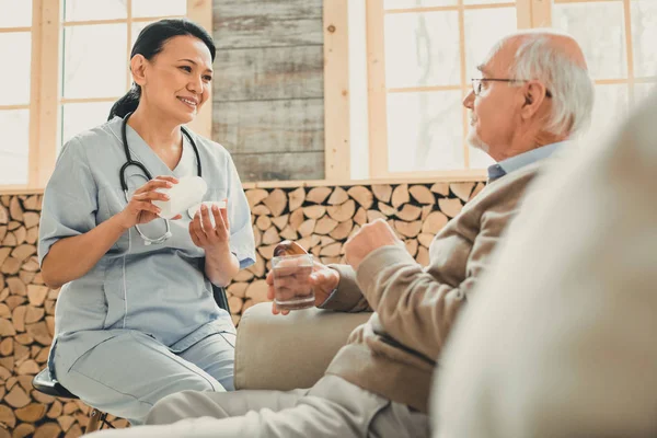 Smiling kind woman sitting in chair against old man