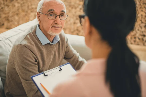 Senior with grey hair directly looking on dark-haired woman — Stock Photo, Image