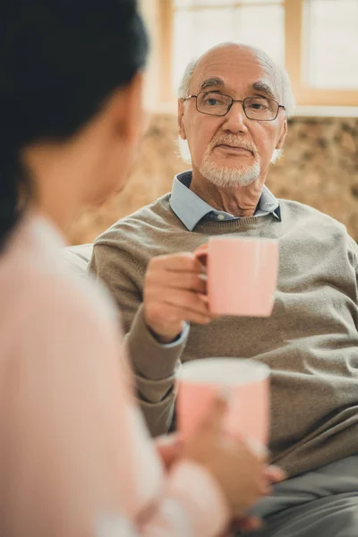 Serieuze senior in bruine trui uitvoering kopje koffie — Stockfoto