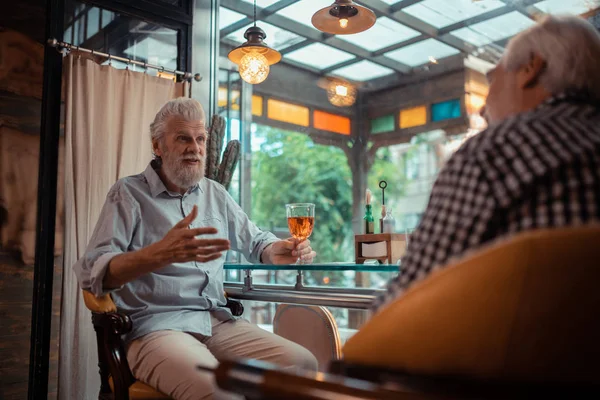 Бородатий чоловік сидить у пабі і п'є алкоголь зі старим другом — стокове фото