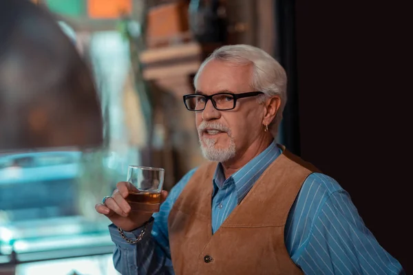 Ο γέρος συνταξιούχος άνθρωπος που φοράει δαχτυλίδι αυτί πίνει ουίσκι — Φωτογραφία Αρχείου
