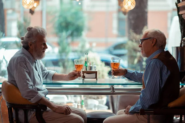 Twee oude vrienden drinken alcohol zitten in de buurt van venster — Stockfoto