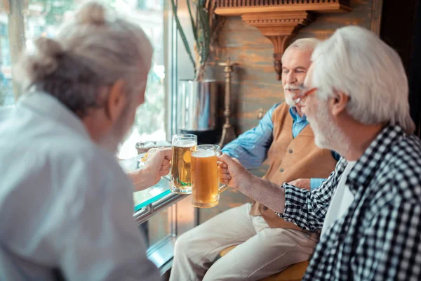 Barbu cheveux gris hommes accrochant des verres avec de la bière — Photo