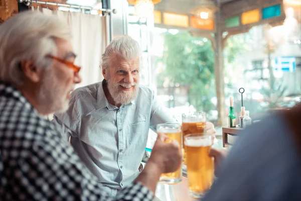 Чоловік посміхається, п'ючи пиво з друзями — стокове фото