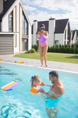 Koca ve kızı havuzda yüzerken anne top fırlatıyor