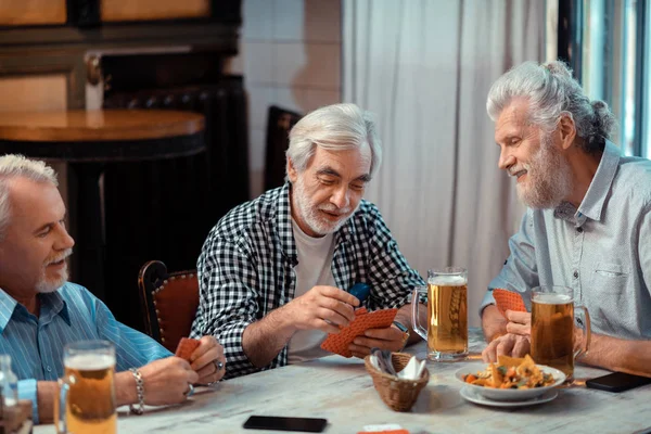 Tre pensionati che giocano a carte bevendo birra — Foto Stock