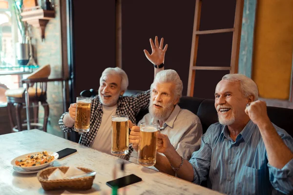 三个足球迷喝啤酒看足球 — 图库照片