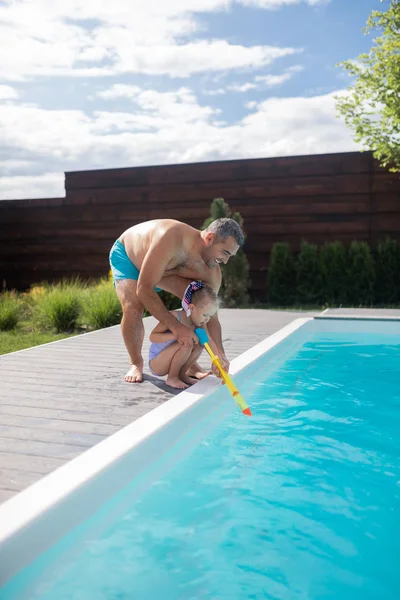 Papi ayudando a su linda chica usando pistola de agua — Foto de Stock