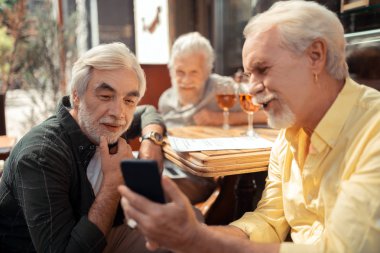 Man showing old photos to his friend while reminding the past clipart
