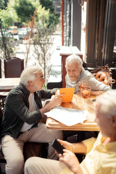 Widok z góry na emerytowanych mężczyzn za pomocą gadżety i picia whisky — Zdjęcie stockowe