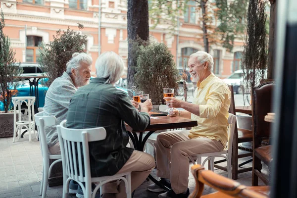 Emerytowany szaro-włosy mężczyźni uśmiechając się i picie alkoholu — Zdjęcie stockowe