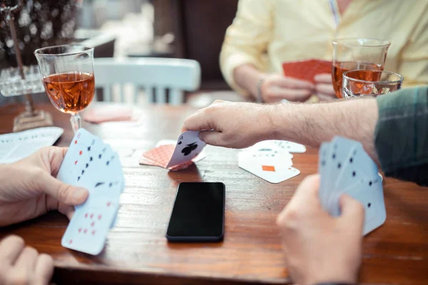 Mann greift nach seiner Hand, während er Karte vom Tisch nimmt — Stockfoto