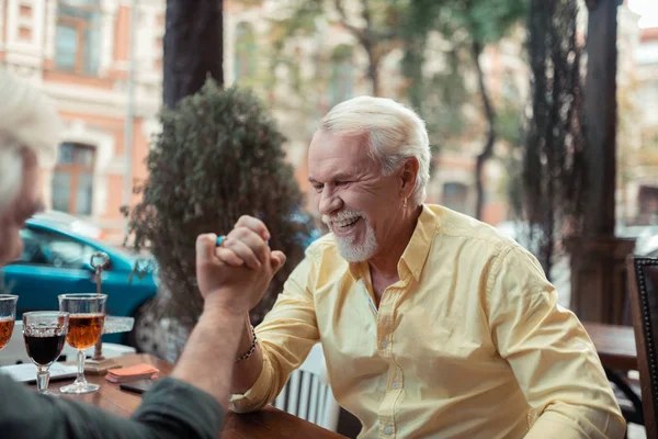 Senior man laughing while winning at arm-wrestling