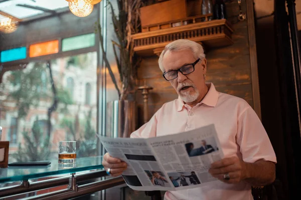 Gri saçlı adam barda oturan gazete okuyor — Stok fotoğraf