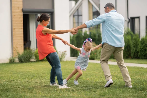 Η κόρη αισθάνεται ευτυχισμένη ενώ χορεύει έξω με τους γονείς — Φωτογραφία Αρχείου