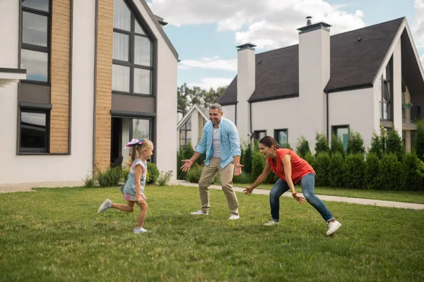 Ouders en dochter spelen verbergen en zoeken buiten in de buurt van huis — Stockfoto