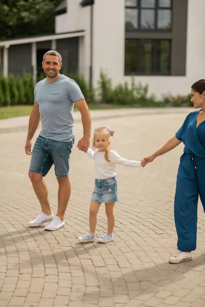 Söt flicka klädd i denim kjol promenader med föräldrarna — Stockfoto