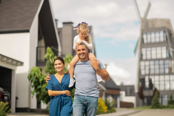 Daughter sitting on neck of father while having family walk — Stock Photo, Image