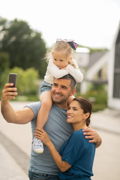 Marido tomando smartphone enquanto faz selfie familiar — Fotografia de Stock