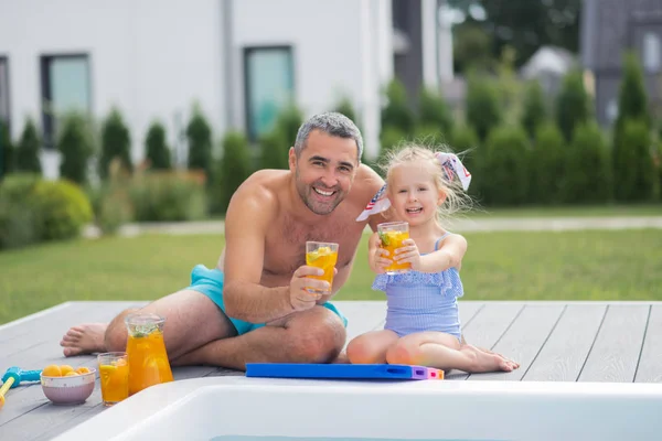 Linda hija tomando el sol y beber jugo con papá — Foto de Stock