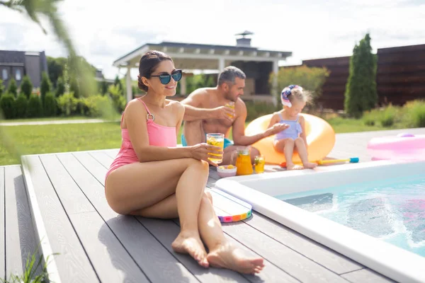 Beautiful slim woman sunbathing near husband and daughter — Stock Photo, Image